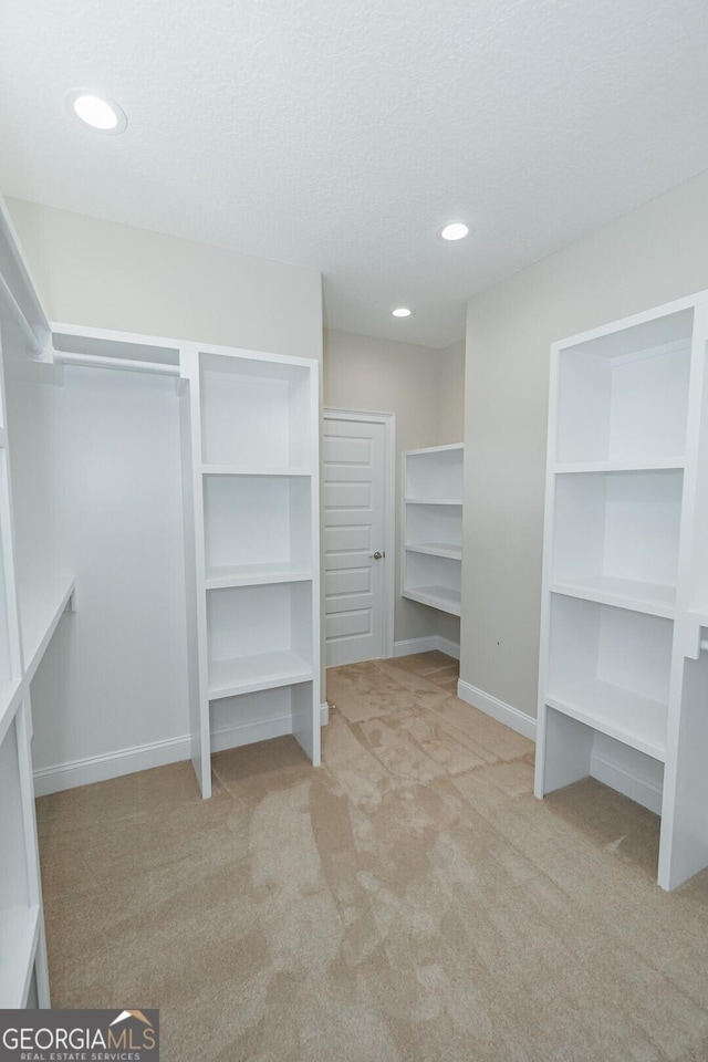 walk in closet featuring light colored carpet