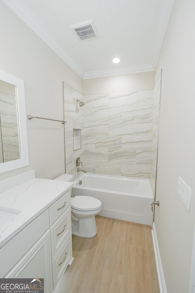 full bathroom with vanity, crown molding, hardwood / wood-style flooring, tiled shower / bath combo, and toilet