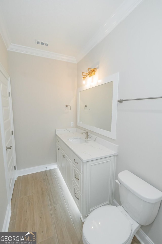 bathroom with toilet, hardwood / wood-style floors, vanity, and ornamental molding