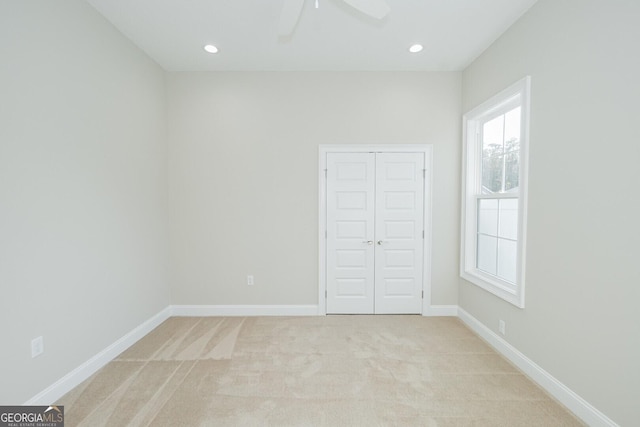 unfurnished bedroom with a closet, light colored carpet, and ceiling fan