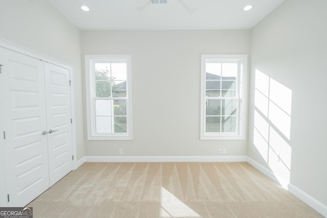 unfurnished bedroom featuring a closet and light colored carpet