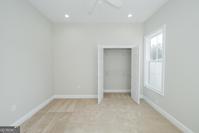 unfurnished bedroom with ceiling fan, a closet, and light carpet