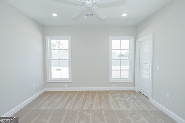 spare room with plenty of natural light, ceiling fan, and light carpet