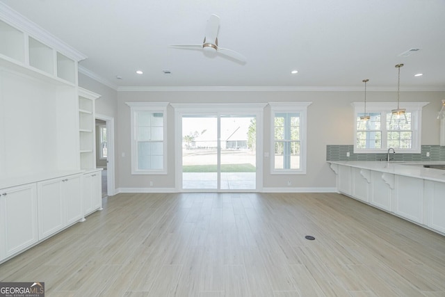 unfurnished living room with ceiling fan, crown molding, sink, and light hardwood / wood-style flooring