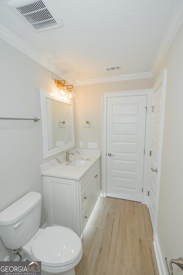 bathroom with vanity, hardwood / wood-style flooring, toilet, and crown molding