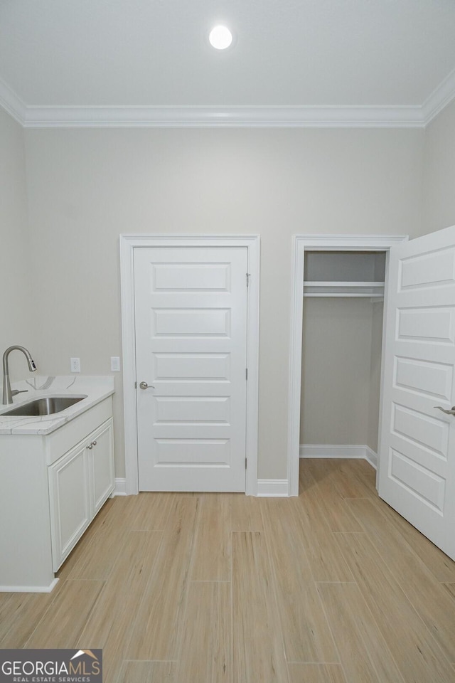 unfurnished bedroom featuring sink, light hardwood / wood-style floors, and ornamental molding