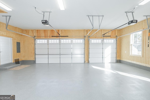 garage with electric panel, a garage door opener, and wood walls