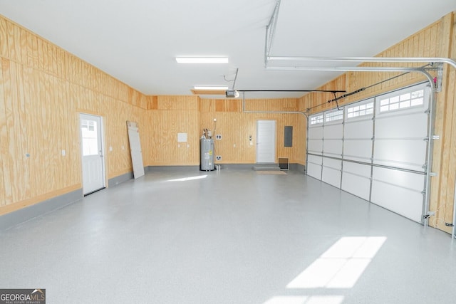 garage featuring a garage door opener, wood walls, and water heater