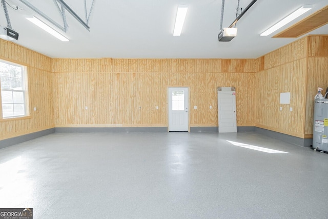 garage with wooden walls, a garage door opener, and water heater