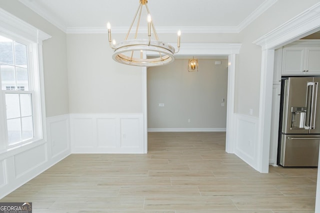 unfurnished dining area with light hardwood / wood-style floors, an inviting chandelier, and ornamental molding