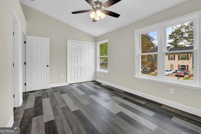 unfurnished bedroom with a closet, a ceiling fan, vaulted ceiling, baseboards, and dark wood-style floors