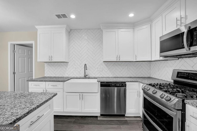 kitchen featuring visible vents, a sink, appliances with stainless steel finishes, white cabinetry, and decorative backsplash