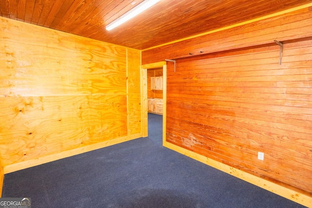 carpeted empty room featuring wood ceiling and wood walls