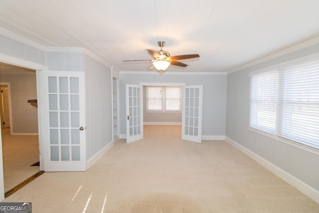 carpeted empty room with french doors, ceiling fan, and ornamental molding