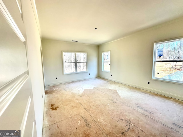 unfurnished room with ornamental molding, a healthy amount of sunlight, visible vents, and baseboards