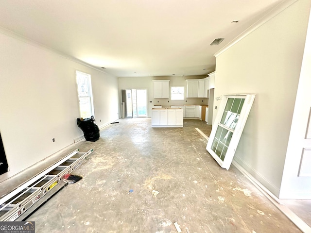 unfurnished living room featuring baseboards and crown molding