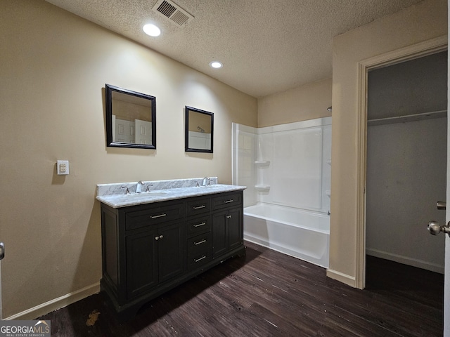 bathroom with vanity,  shower combination, wood-type flooring, and a textured ceiling