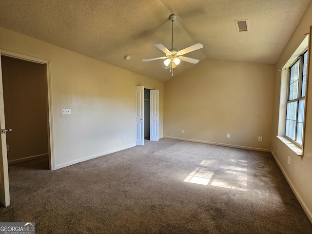 carpeted spare room featuring a textured ceiling, vaulted ceiling, and ceiling fan