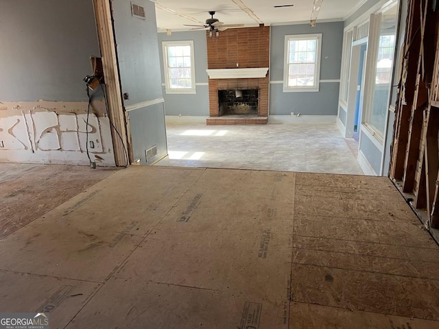 unfurnished living room with a wealth of natural light, ceiling fan, and a brick fireplace