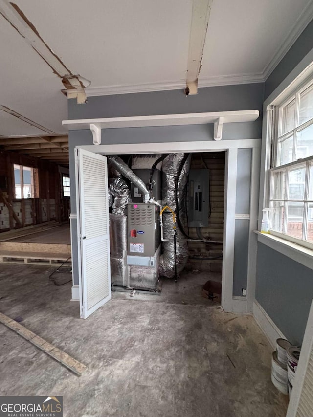 basement featuring electric panel, crown molding, and heating unit