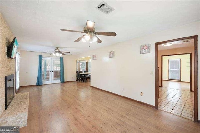 unfurnished living room with hardwood / wood-style floors, ceiling fan, and french doors