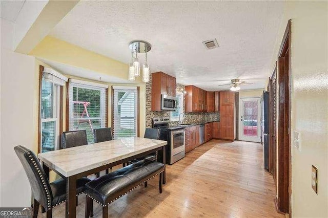 dining room featuring ceiling fan, sink, light wood-type flooring, and a textured ceiling