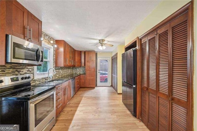 kitchen with backsplash, sink, light hardwood / wood-style flooring, and appliances with stainless steel finishes