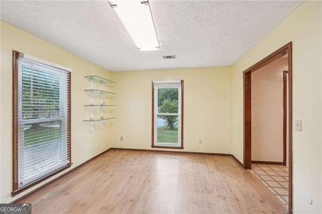 empty room featuring light wood-type flooring and a textured ceiling