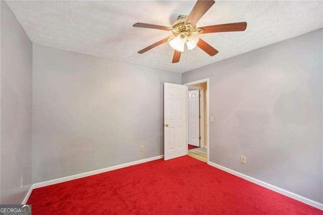 carpeted empty room featuring ceiling fan and a textured ceiling