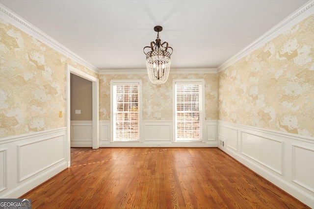 unfurnished dining area with hardwood / wood-style flooring, crown molding, and a notable chandelier