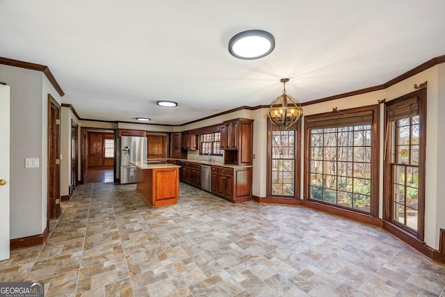 kitchen with a notable chandelier, crown molding, pendant lighting, a kitchen island, and appliances with stainless steel finishes