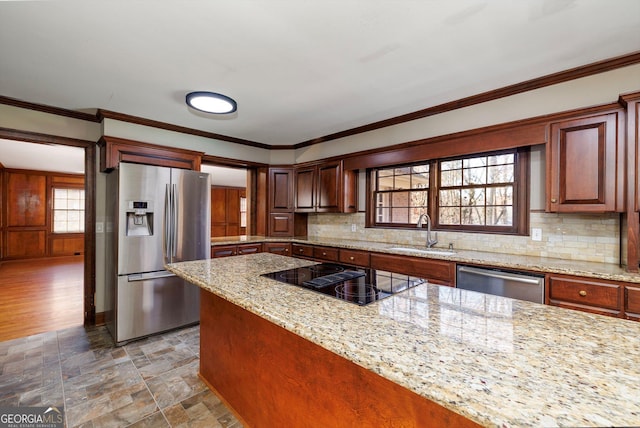 kitchen featuring light stone counters, sink, stainless steel appliances, and ornamental molding