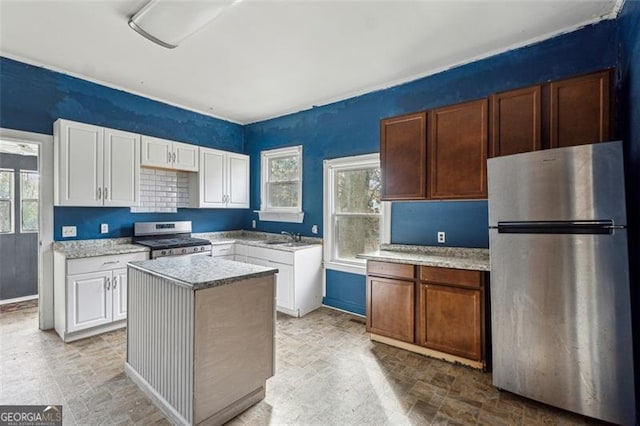 kitchen featuring white cabinets, a healthy amount of sunlight, a kitchen island, and stainless steel appliances