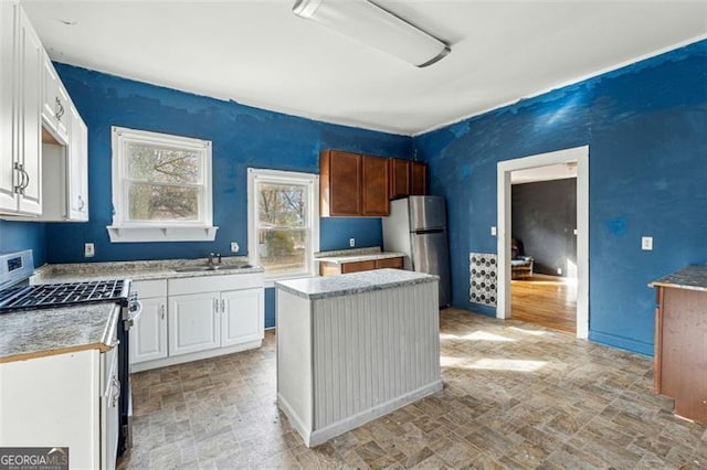 kitchen featuring stainless steel fridge, sink, white cabinets, a center island, and white range with gas stovetop