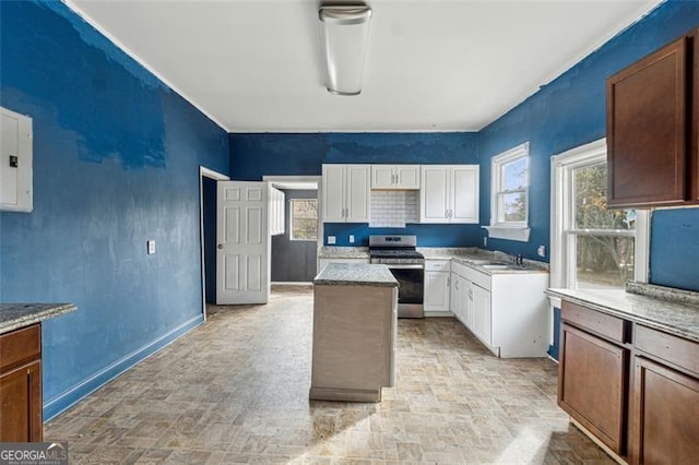 kitchen with gas stove, sink, a kitchen island, electric panel, and white cabinets