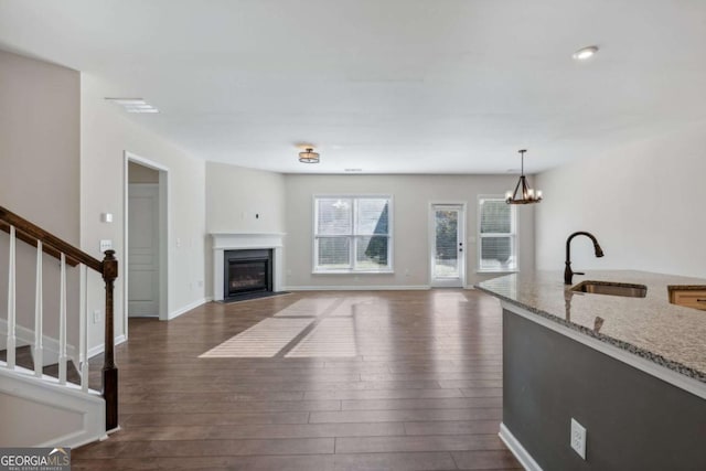 living room featuring sink, dark wood-type flooring, and a notable chandelier