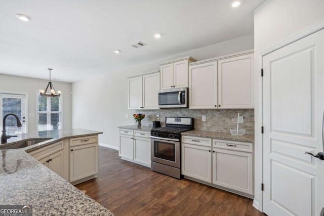 kitchen featuring appliances with stainless steel finishes, dark hardwood / wood-style floors, light stone counters, and sink