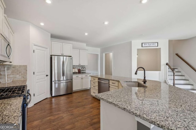 kitchen with light stone countertops, appliances with stainless steel finishes, backsplash, sink, and dark hardwood / wood-style floors