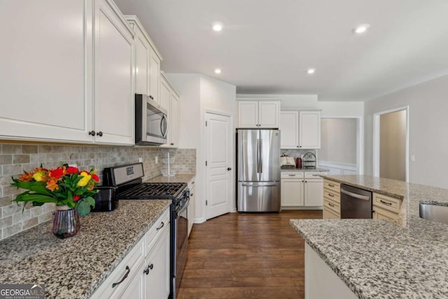 kitchen with light stone countertops, dark hardwood / wood-style flooring, stainless steel appliances, and white cabinets