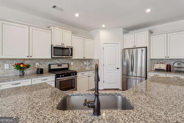 kitchen with decorative backsplash, light stone counters, and stainless steel appliances