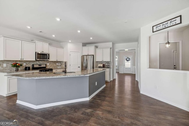 kitchen featuring a kitchen island with sink, dark wood-type flooring, sink, appliances with stainless steel finishes, and white cabinetry