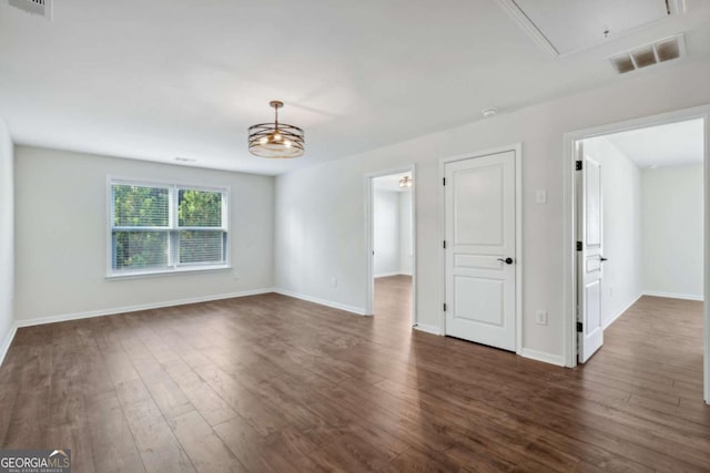 unfurnished room featuring a chandelier and dark hardwood / wood-style floors