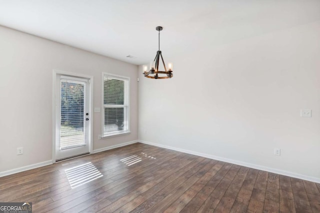 unfurnished room with a chandelier and dark hardwood / wood-style floors