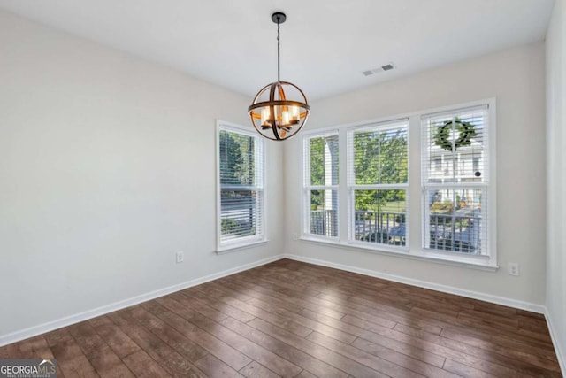 unfurnished dining area featuring dark hardwood / wood-style flooring and an inviting chandelier