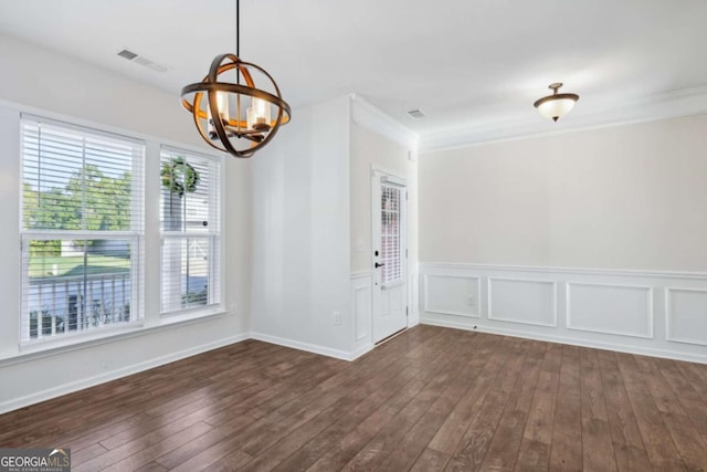 spare room featuring a notable chandelier, dark hardwood / wood-style flooring, and ornamental molding