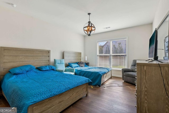 bedroom with dark hardwood / wood-style flooring and a notable chandelier