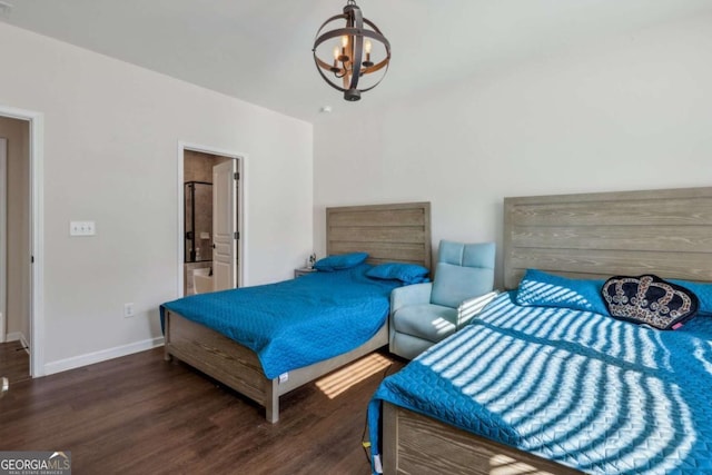 bedroom featuring ensuite bath, dark wood-type flooring, and an inviting chandelier