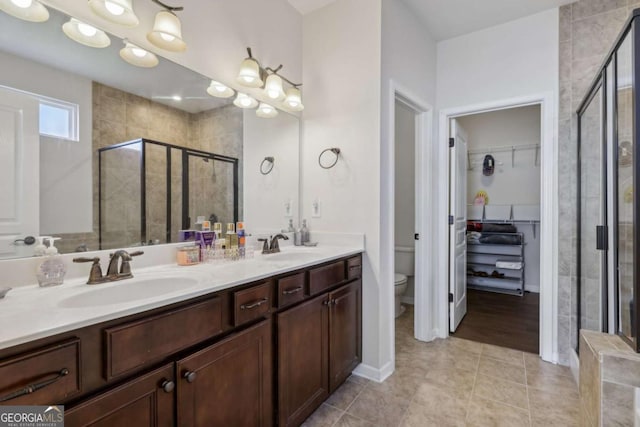 bathroom with toilet, vanity, tile patterned floors, and a shower with shower door