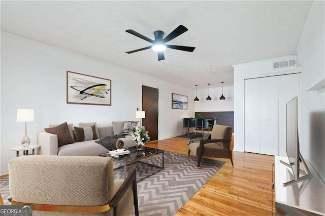 living room with hardwood / wood-style floors, ceiling fan, and a textured ceiling