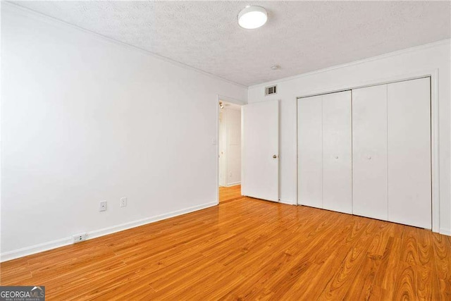 unfurnished bedroom featuring a textured ceiling, light hardwood / wood-style flooring, and a closet